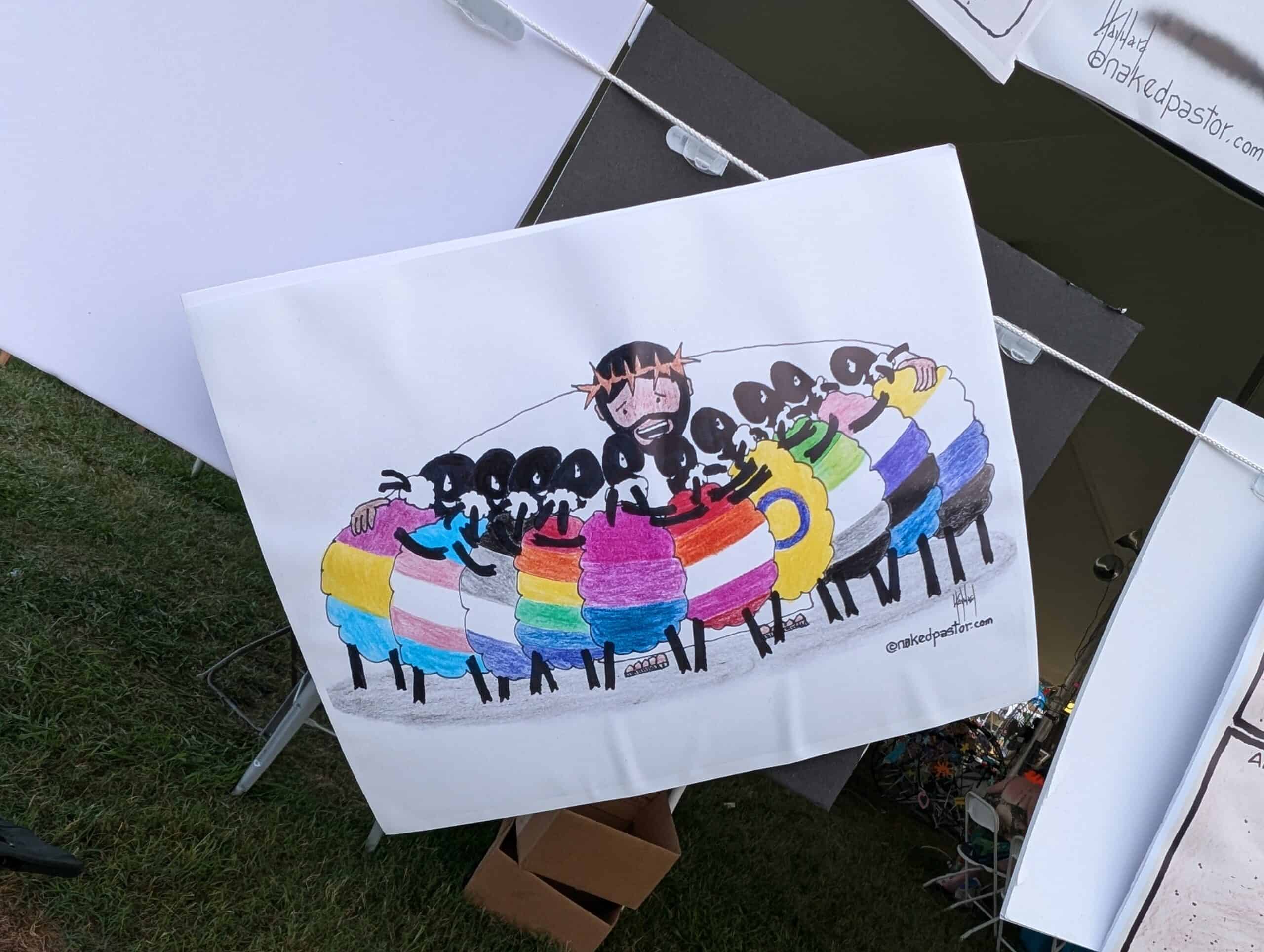 PXL_20240713_212855747 Cartoon depiction of a smiling person with sheep, wearing LGBTQ+ and inclusive flag patterns. Displayed at an art stall outdoors.