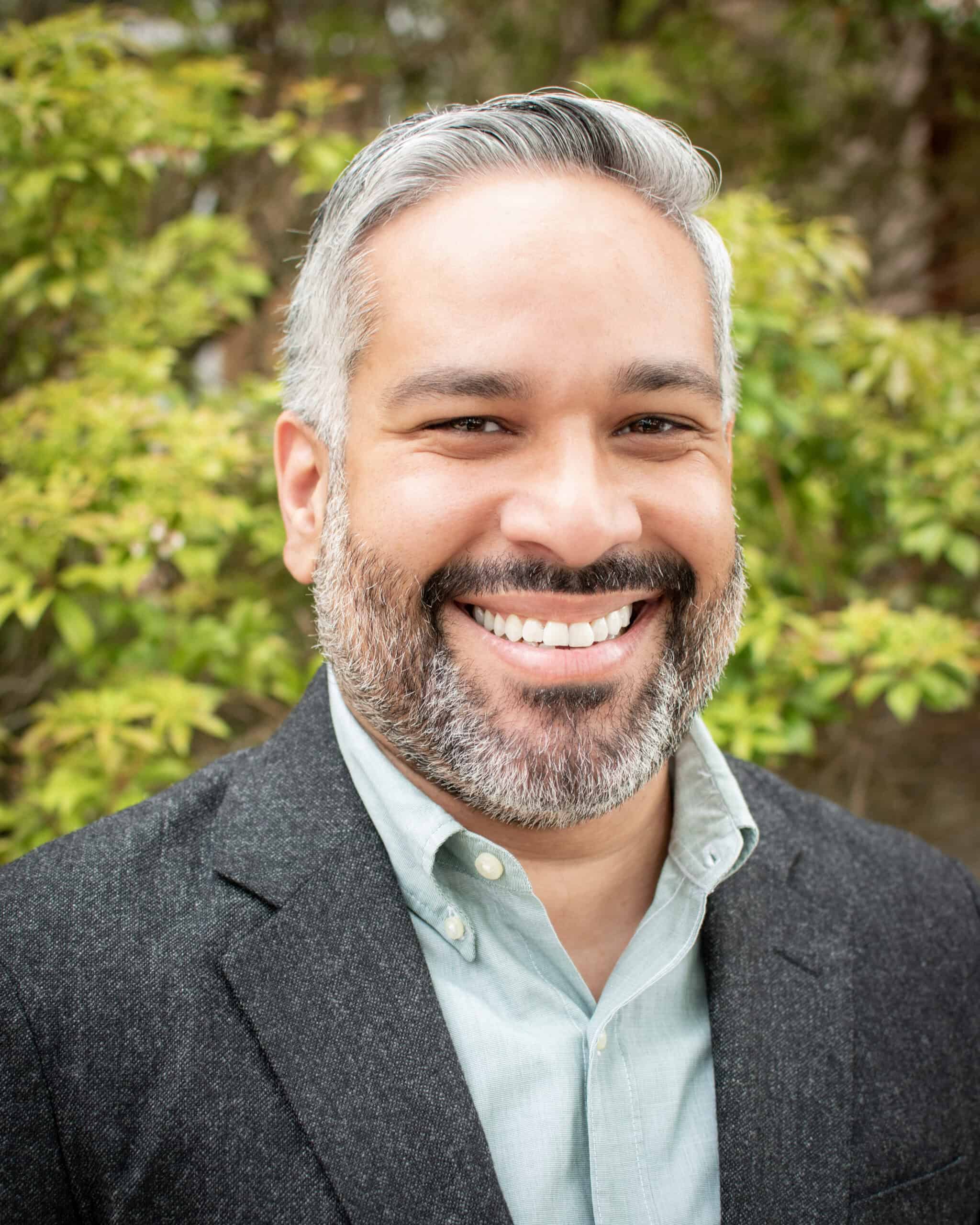 Abreu Rosario - Headshot Celebrating More Light Presbyterians with a smiling man outdoors in natural light.